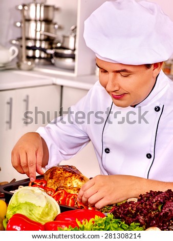 Handsome man in chef hat cooking chicken.