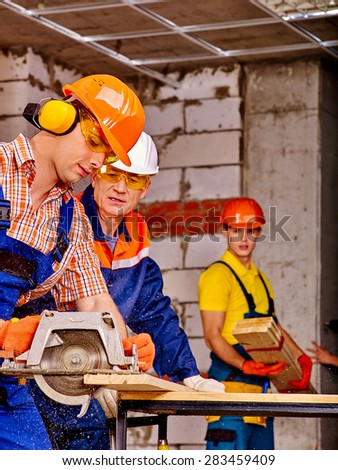Happy group people  builder with circular saw working indoor.