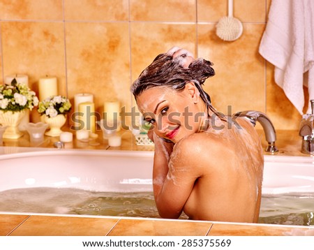 Woman washes her head at home bathroom. Water in bath.