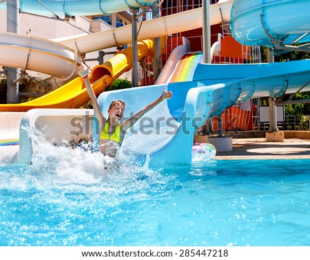 Happy child girl in bikini sliding water park.