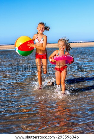 Happy two children girl holding hands running on  beach.