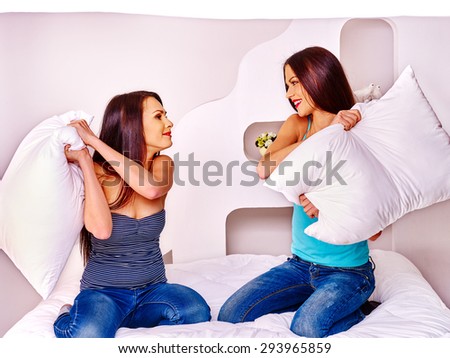 Two lesbian women at pillow fights in bedroom. Indoor.