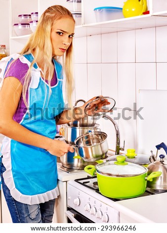 Unhappy tired woman preparing food at kitchen. Girl does not know what to cook