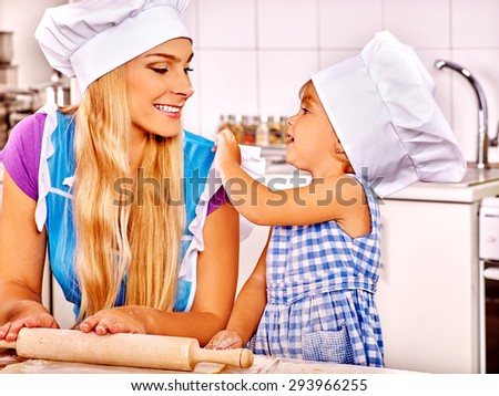 Mother and daughter baking cookies. Mom gently looking on her child