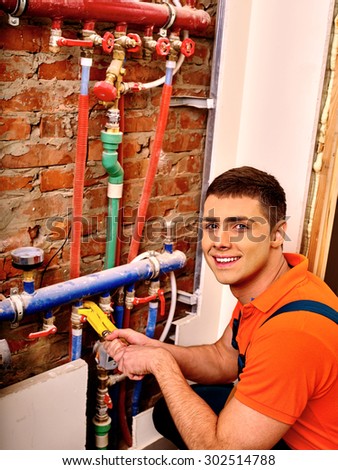 Men builder in orange fixing heating system with special tool.