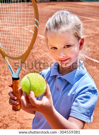 Sport kids girl with racket and ball on  brown  court. Child tennis player.