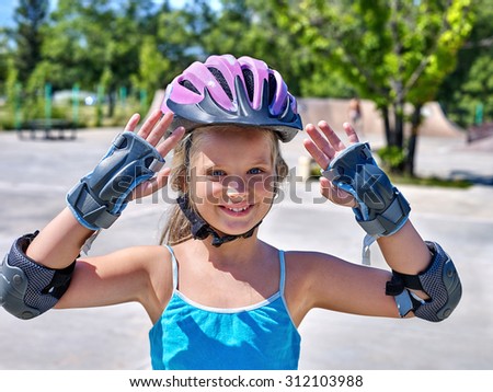 Portrait of girl in sport helmet riding on roller skates in skatepark.