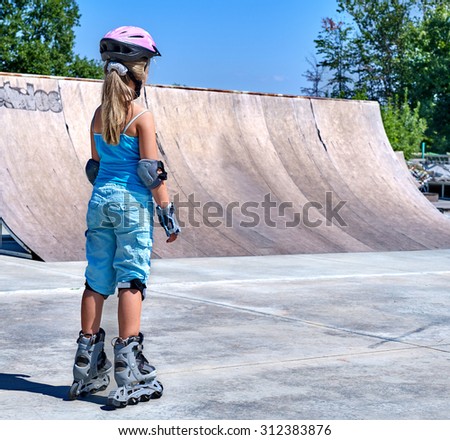 Girl riding on roller skates in skatepark. View from the back