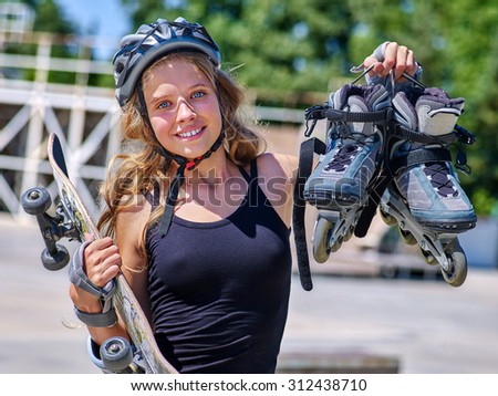 Girl holding  skate and roller skates in sport park