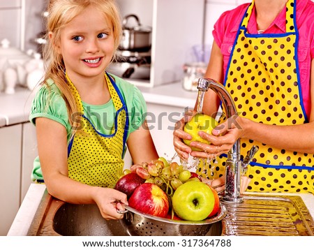 Happy children washing fruit at kitchen.