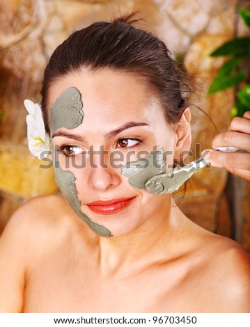 Beautiful girl having clay body mask apply by beautician.