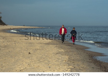 SARBINOWO, POLAND - CIRCA MAY 2013: couple walking in the morning the banks of the Baltic Sea circa may 2013 in Sarbinowo. Walking the sea is a very popular way to relax at the Polish seaside.