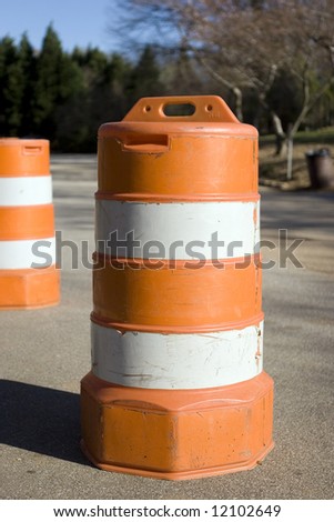 An orange traffic barrel on a small road.