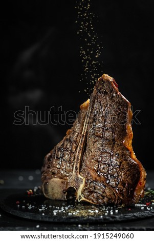 Aged Barbecue Porterhouse Steak. Beef T-Bone juicy steak. Chef sprinkles with seasoning for roasting. Classic American dish. Sale of meat, butcher shop. vertical image, place for text.