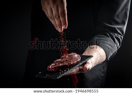 Chef hands cooking meat steak and adding seasoning in a freeze motion. Fresh raw Prime Black Angus beef rump steak. banner, menu recipe.