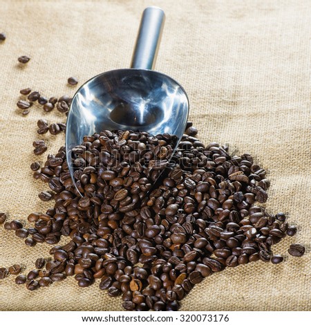 Coffee beans with measuring scoop on burlap