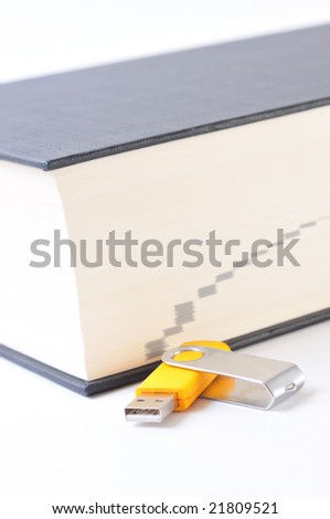 Yellow USB memory stick near a dictionary, detail view, isolated on white background.