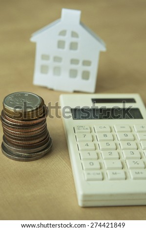 Coins,calculator  and blurred house model for house loan concept