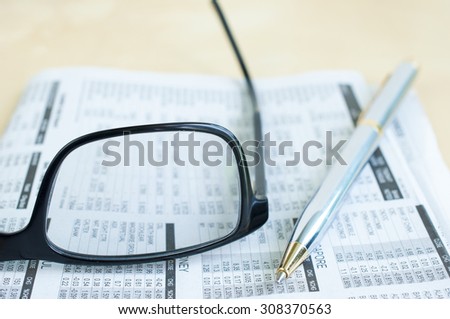 Soft focus pen and eyeglasses on blur newspaper background