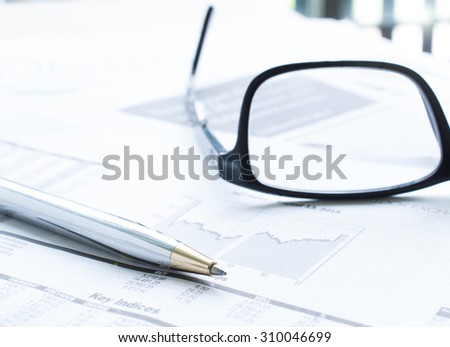 Selective focus pen with blur eyeglasses and newspaper background