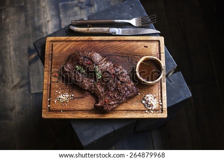 Beef steak. Piece of  Grilled BBQ beef marinated in spices and herbs on a rustic wooden board over rough wooden desk with a copy space. Top view