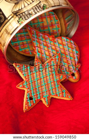 Checked red and green Christmas cookies in retro cookie jar. Gingerbreads are hand made and frosted with royal icing. Sweet and elegant composition on red silk.