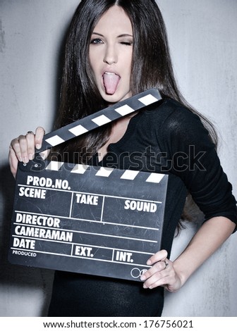 Portrait of sensuality woman with beautiful long dark hair, posing at studio, wearing black, holding clapperboard