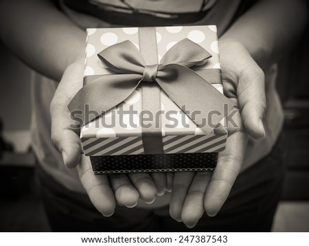 Woman holding a gift box in a gesture of giving with black and white effect