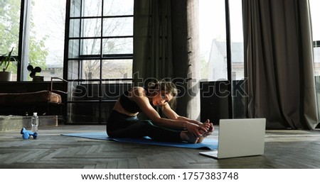 Pretty young woman stretching on mat on floor in living room and recording video training online for female. Quarantine sport video lesson. Training and working out via internet coaching. Photo stock © 
