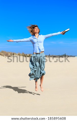 young student girl is jumping up in the air at the beach