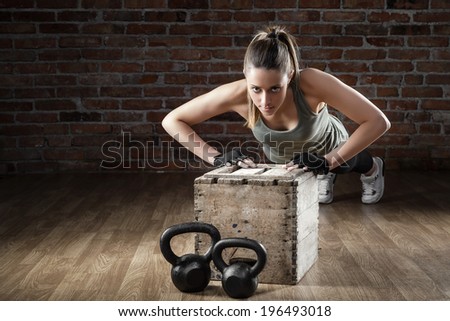 Portrait of a Young fit woman pushing up on brick background