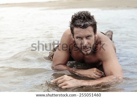 Close up Handsome Athletic Army with No Shirt Crawling at Sea Water While Looking at the Camera.