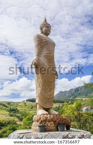 the gold buddha statue standing under the sun and blue sky at Thai temple. This buddha is made from donation money from the people in the village