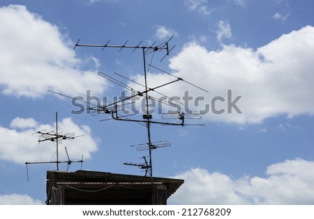 the Antenna TV on the top roof of the house under the blue sky and white clouds