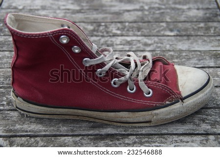Old torn vintage maroon red canvas sneaker - teenager shoe