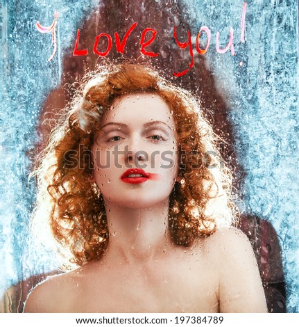Sexy Beautiful Red haired Woman Behind Glass with Water Drops. Wet Glass in Drops with an Inscription I Love You