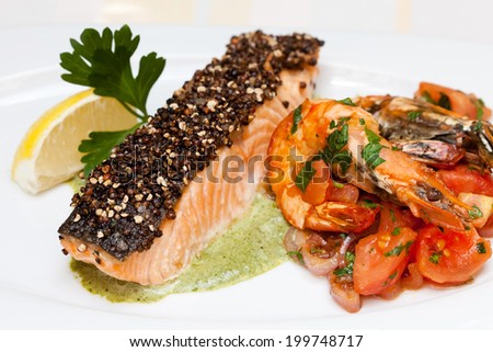 Salmon fillet with spinach sauce and fried shrimp on white background.