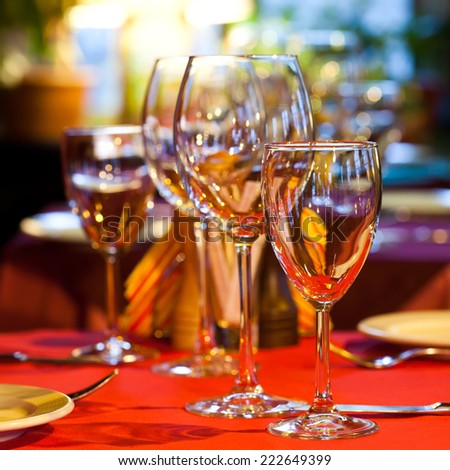 Romantic interior. Table in a restaurant with a red tablecloth, napkins, wine glasses and cutlery.