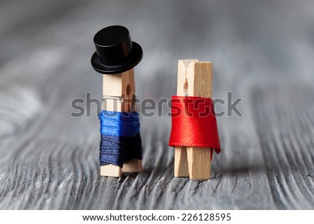 Gentleman in hat and woman in red dress: clothespins. Meeting. Vintage wood background. Soft focus.