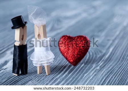 Romantic couple. Wedding invitation. Valentines day. Man, woman and read heart. Groom in black suit and bride in white dress. Clothespins. (Soft focus)