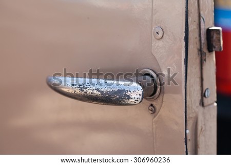 Detail image of rusty old beige truck door with shabby, chrome handle. Opened automobile door. soft focus, closeup