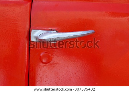 Door handle lock. Vintage auto parts of lorry truck. Closed. Silver, retro automobile door handle. Red paint metal background. soft focus, close-up