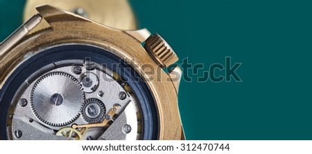 Detailed view of ancient clock parts. Macro shot of the interior of an old pocket watch with a hand-wound mechanical movement. copy space. dark green background.
