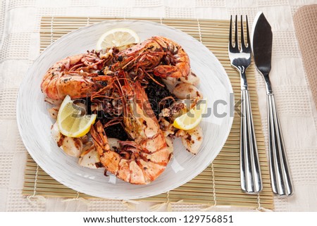 Jumbo prawns and grilled squids with black rice on restaurant table
