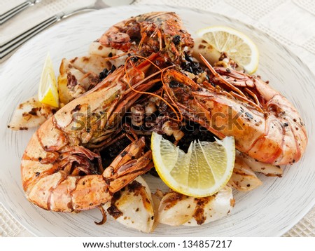 Jumbo prawns and grilled squids with black rice and lemon, close-up