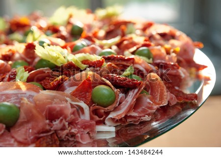 Platter with cured ham with olives and sun dried tomatoes