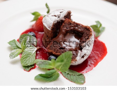 Chocolate fondant with berry sauce cut in halves with molten chocolate inside