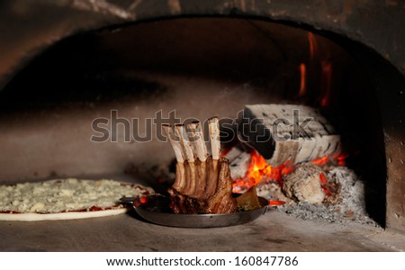 Rack of lamb and pizza in traditional wood fire oven