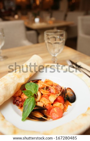 Seafood pasta cooked under pizza dough leaf on restaurant table