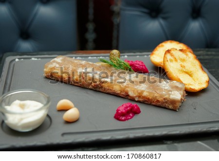 Meat aspic with baked potatoes and horseradish on pub table